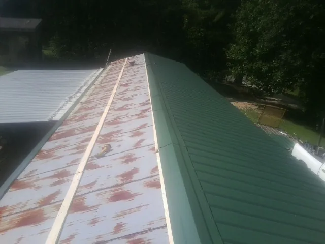 Old rusted panels beside newly installed green metal roofing — Wind Damage Roof Repair by Roofing Brothers in Burkburnett