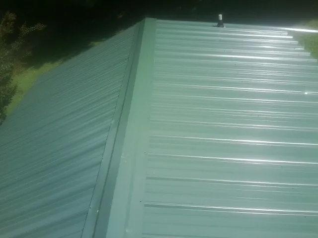 New green metal panels meeting at the ridge of a roof — Flat Roof Repair work by our crew in Burkburnett