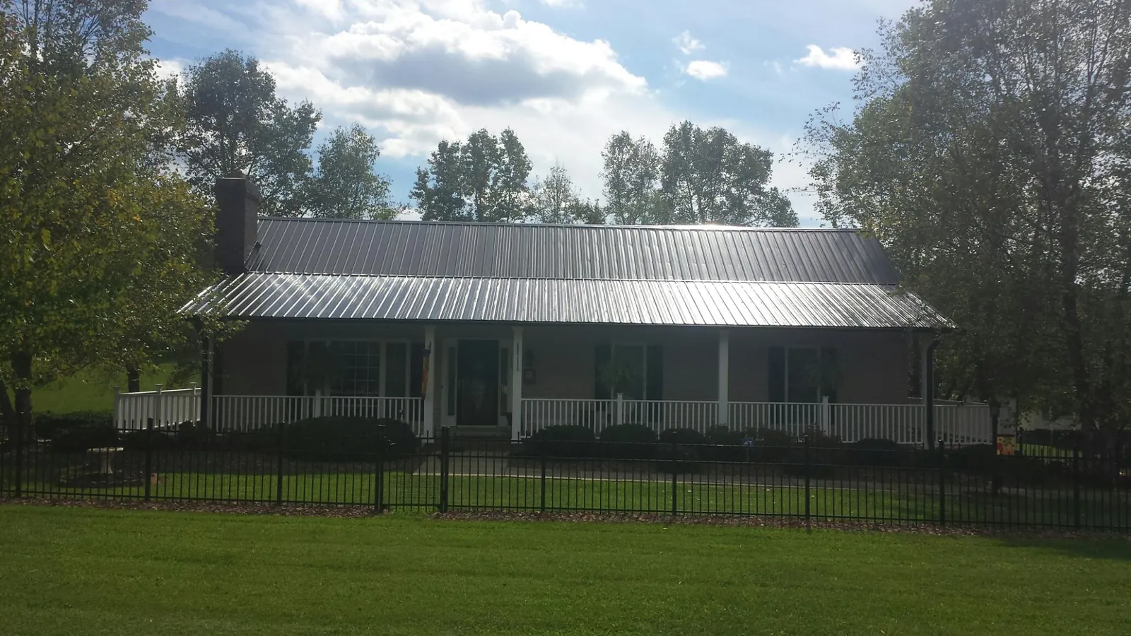 Gray metal roof on a brick ranch with a full width front porch — Gutter Guard Installation work by our crew in Burkburnett