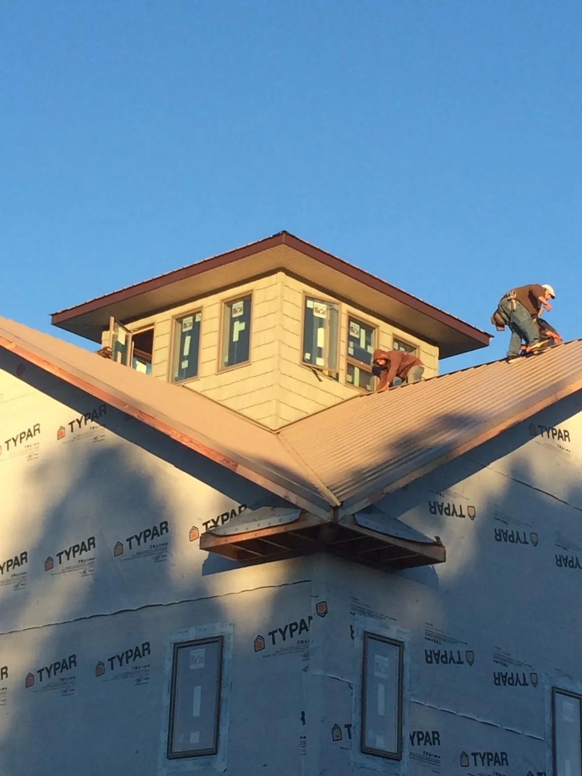 Roofers working around a rooftop cupola on a new metal roof at sunset — Roof Waterproofing in Burkburnett by Roofing Brothers